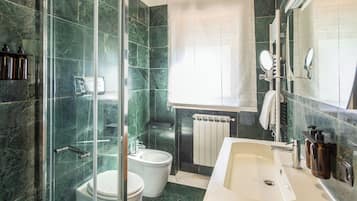 Un baño moderno con cabina de ducha de vidrio, inodoro independiente, tocador con espejo y bañera.