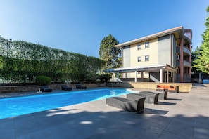 A swimming pool with lounge chairs and a covered patio area.