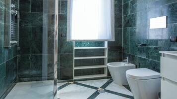 Un baño moderno con cabina de ducha de vidrio, una bañera independiente y un inodoro.