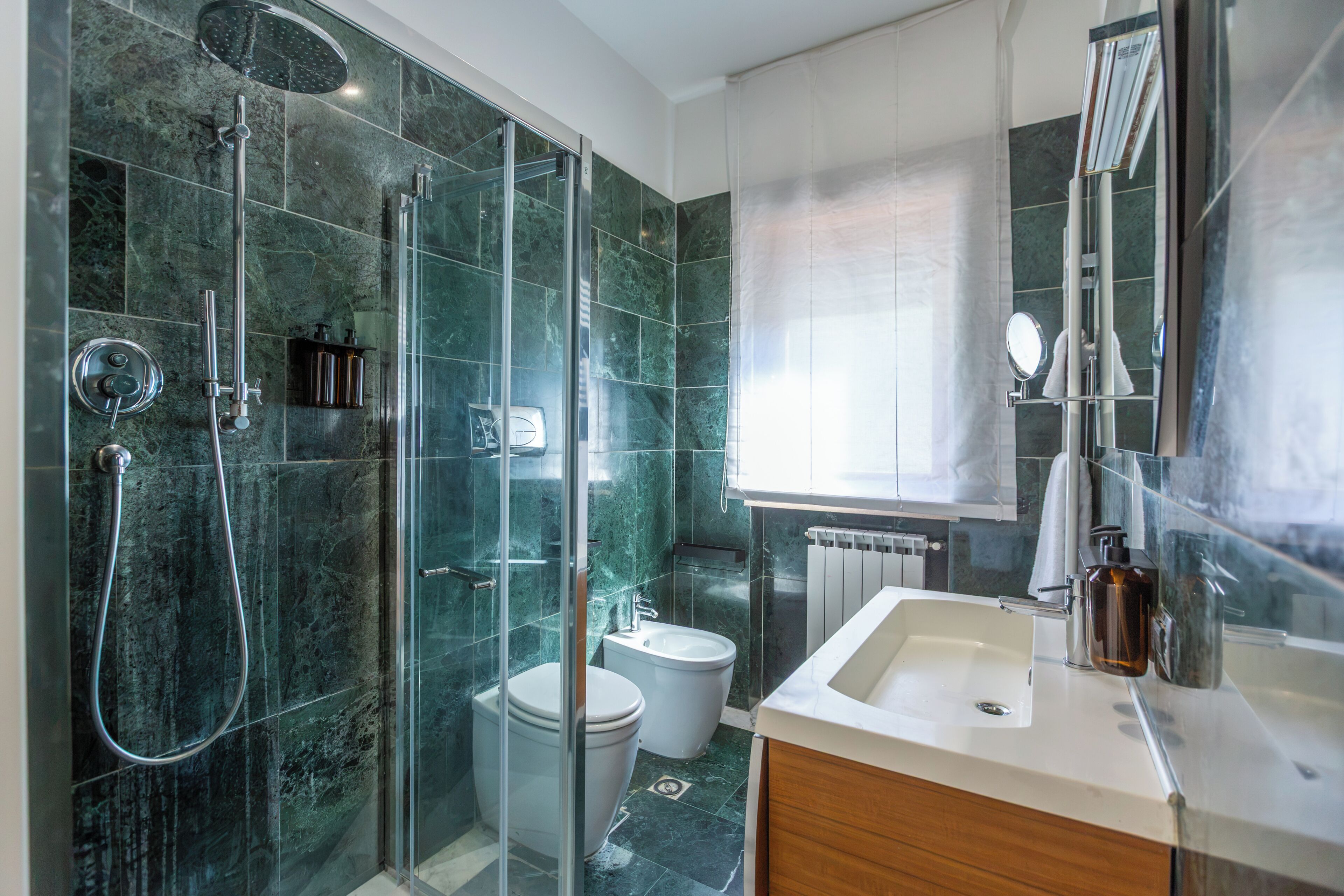 A modern bathroom with a glass-enclosed shower, a toilet, and a sink with a mirror.