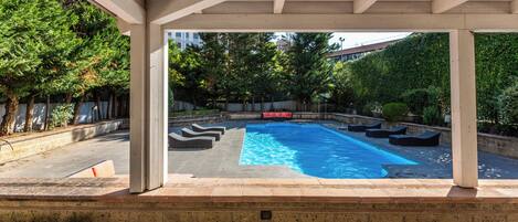 A covered outdoor swimming pool with lounge chairs and a red sofa.