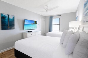 A hotel room with a bed, a television, a ceiling fan, and a window with curtains. - Phoenix Iii 3064 2 Bedroom Condo (Orange Beach)