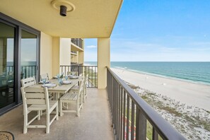 A balcony with a table set for dining, overlooking a beach with a clear view of the ocean. - Phoenix Iii 3064 2 Bedroom Condo (Orange Beach)