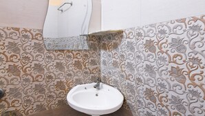 Een badkamer met een witte wasbak, decoratieve betegeling en een spiegel.