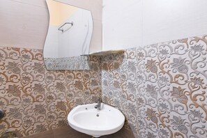 A bathroom with a white sink, ornate patterned tiles, and a mirror. - Saver Double Utsho Hotel (Jalpaiguri)