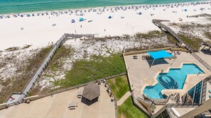 A beach resort with a swimming pool, beach umbrellas, and a wooden boardwalk. - Phoenix Iii 3101 3 Bedroom Condo (Orange Beach)