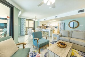 A modern living room with a sofa, armchair, and a dining area with a table and chairs. - Phoenix Iii 3101 3 Bedroom Condo (Orange Beach)
