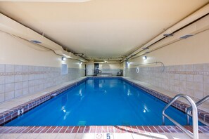 Ein Schwimmbecken mit einer 1,5 Meter Tiefenmarkierung, gefliesten Wänden und einer Decke mit sichtbaren Lüftungskanälen.