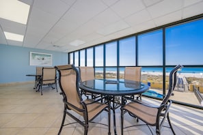 Ein Konferenzraum mit Glastisch und Stühlen, großen Fenstern mit Blick auf den Strand und einem gefliesten Boden.