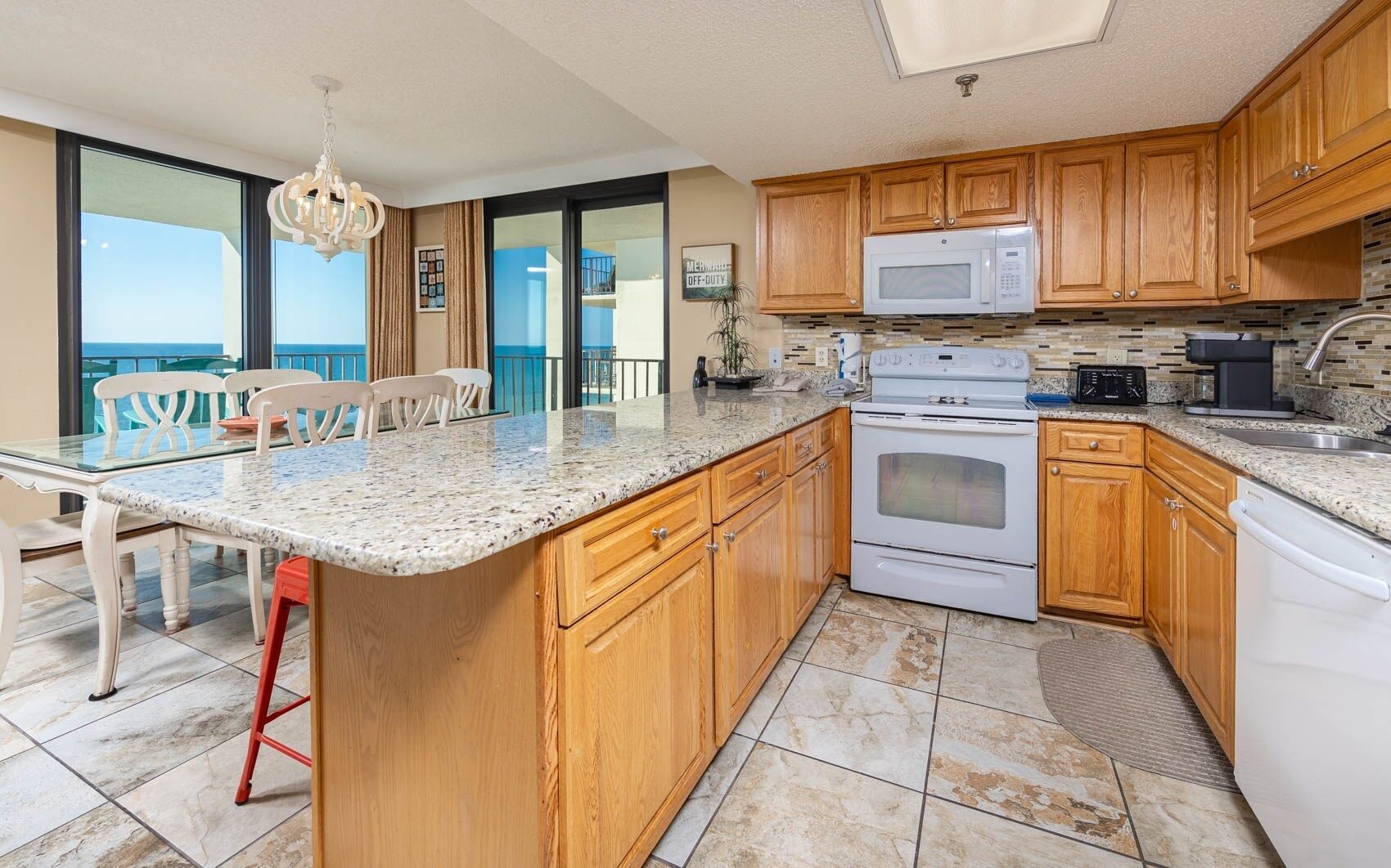 A kitchen with wooden cabinets, a granite countertop, a microwave, an oven, and a dishwasher.