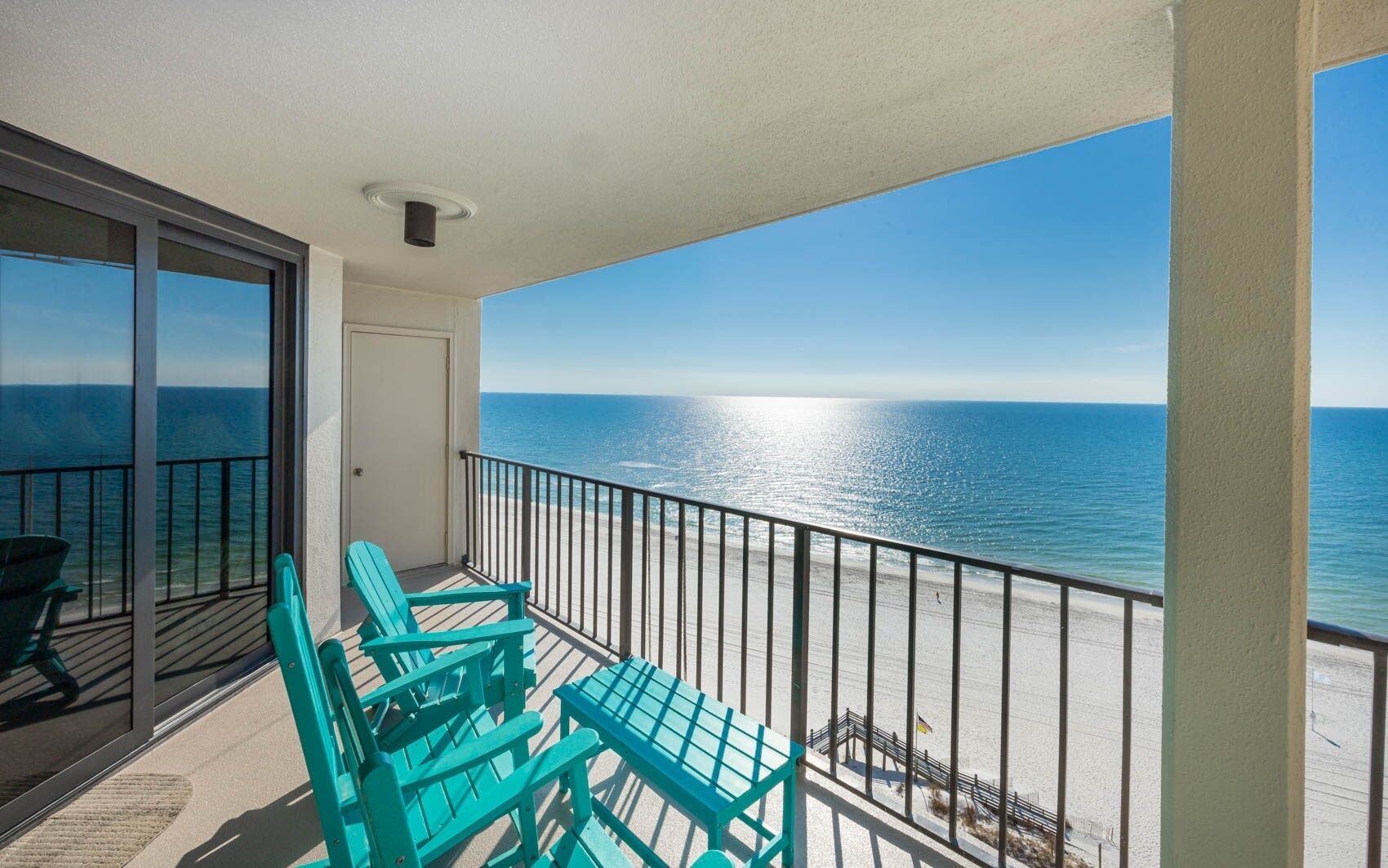 A balcony with a view of the ocean, a door, and two chairs.