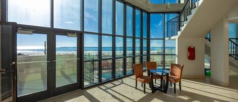 A spacious room with large floor-to-ceiling windows offering a view of the beach and ocean.