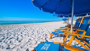 A beach with blue umbrellas and lounge chairs. - Phoenix Iv 4075 3 Bedroom Condo (Orange Beach)