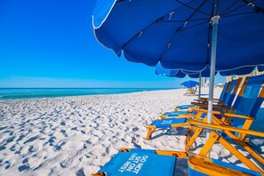 A beach with blue umbrellas and lounge chairs. - Phoenix Iv 4075 3 Bedroom Condo (Orange Beach)