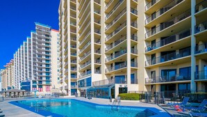 A multi-story hotel with a swimming pool, balconies, and a clear blue sky. - Phoenix Iv 4075 3 Bedroom Condo (Orange Beach)