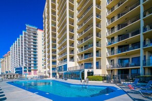 A multi-story hotel with a swimming pool, balconies, and a clear blue sky. - Phoenix Iv 4075 3 Bedroom Condo (Orange Beach)