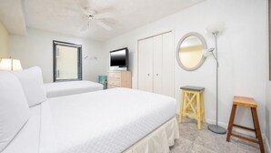 A bedroom with two beds, a ceiling fan, a television, a wardrobe, a mirror, and a floor lamp. - Phoenix Iv 4075 3 Bedroom Condo (Orange Beach)