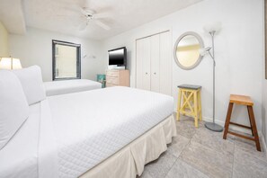 A bedroom with two beds, a ceiling fan, a television, a wardrobe, a mirror, and a floor lamp. - Phoenix Iv 4075 3 Bedroom Condo (Orange Beach)