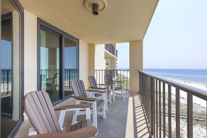 A balcony with chairs and a table, overlooking a beach. - Phoenix Iii 3068 2 Bedroom Condo (Orange Beach)