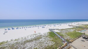 A beach with a boardwalk, umbrellas, and lounge chairs. - Phoenix Iii 3068 2 Bedroom Condo (Orange Beach)
