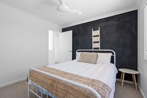 A bedroom with a bed, a white ceiling fan, a black accent wall, a small bedside table, and a window. - 17 Elluisa Close : 4  BR, 3  BA House in Forster, Sleeps 8 (Forster)
