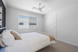 A bedroom with a bed, a window, a ceiling fan, and a door. - 17 Elluisa Close : 4  BR, 3  BA House in Forster, Sleeps 8 (Forster)