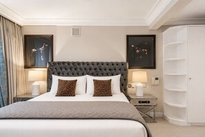 A hotel room with a large bed, two bedside lamps, a wardrobe, and two framed pictures on the wall. - Luxury Holland Park 3-bed With Private Balcony (London)