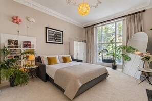 A bedroom with a bed, bedside tables, a bookshelf, a large window, and a mirror. - Luxury Holland Park 3-bed With Private Balcony (London)