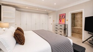 Ein Schlafzimmer mit Bett, Kleiderschrank, Kommode und Fernseher.
