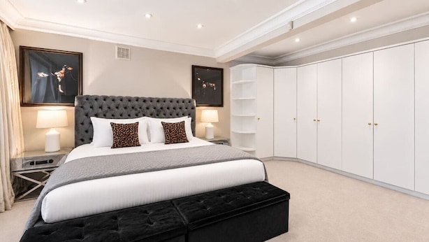 Ein Schlafzimmer mit einem großen Bett, einer Kommode, einem Kleiderschrank und zwei Nachttischen mit Lampen.
