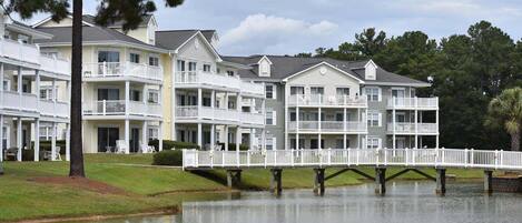 A multi-story hotel with balconies, a dock, and a body of water.