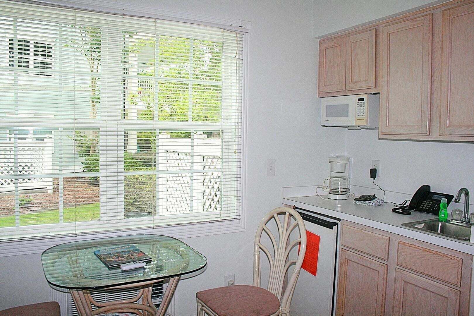Una cocina compacta con una mesa de comedor, microondas, cafetera y lavabo.