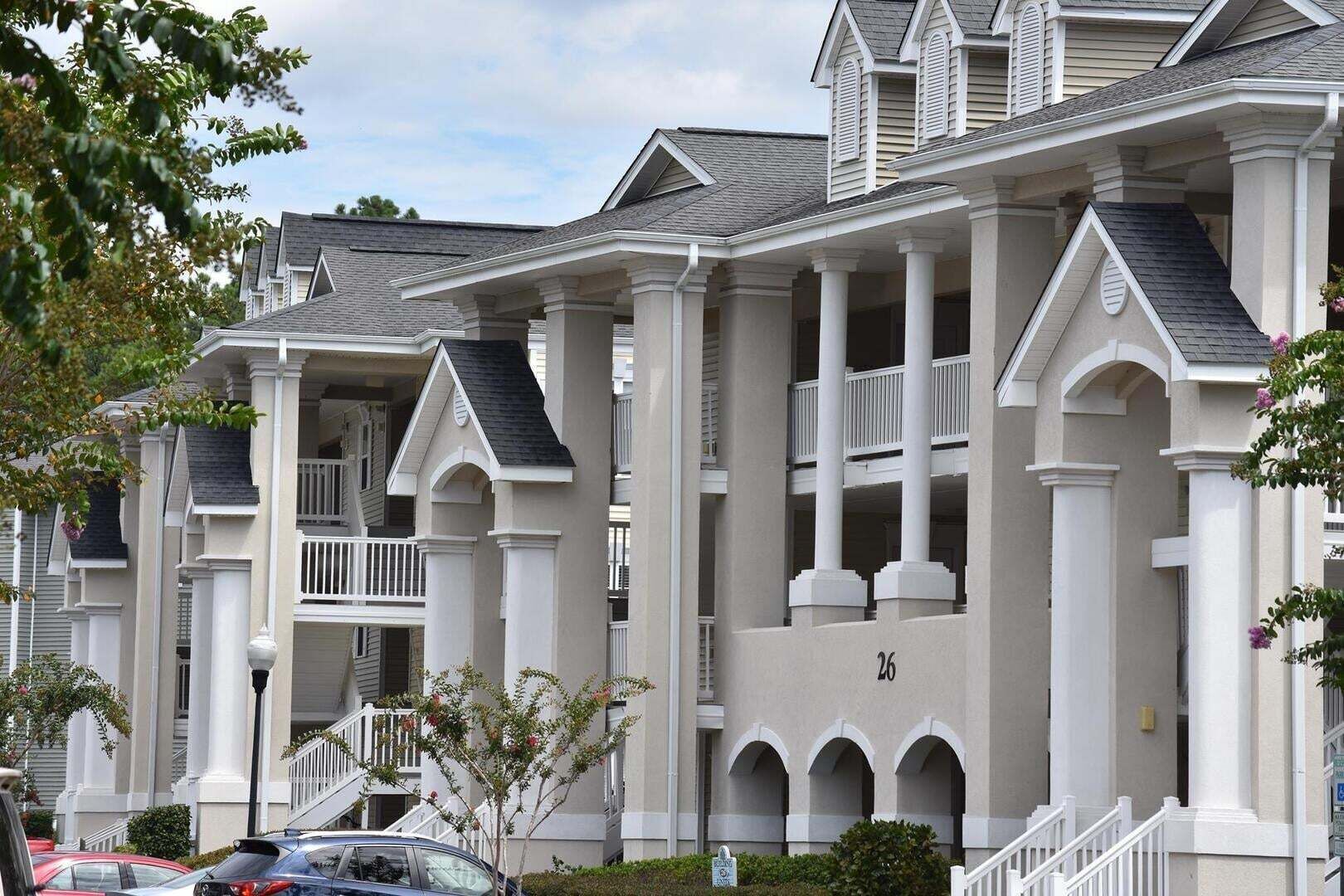 Ein mehrstöckiges Wohngebäude mit symmetrischer Fassade, mehreren Balkonen und einem zentralen Eingang.