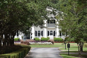 A white building with a central entrance, surrounded by well-maintained lawns and trees. - 501 2 Bedroom Villa (Calabash)