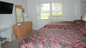 Ein Schlafzimmer mit Bett, Schminktisch, Fernseher und Fenster.