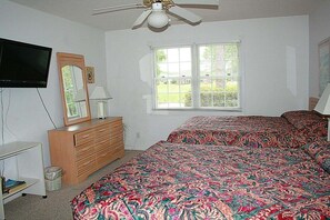 A bedroom with a bed, dresser, television, and window. - 501 2 Bedroom Villa (Calabash)