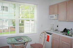 A compact kitchen with a dining table, a microwave, a coffee maker, and a sink. - 501 2 Bedroom Villa (Calabash)