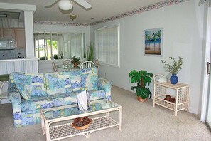 A living room with a patterned sofa, a coffee table, a potted plant, and a painting on the wall. - 501m 1 Bedroom Condo (Calabash)