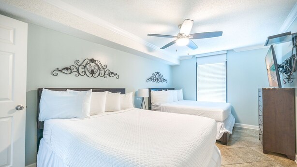 A hotel room with two beds, a ceiling fan, a wall-mounted artwork, and a dresser. - Phoenix East 511 3 Bedroom Condo (Orange Beach)