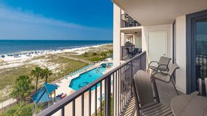 Un balcon avec vue sur une plage et une piscine.