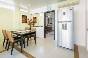 A modern kitchen with a stainless steel refrigerator, a dining table with chairs, and a mirror on the wall. - 1 Bedroom Beach Villa Apartment (Ko Chang)