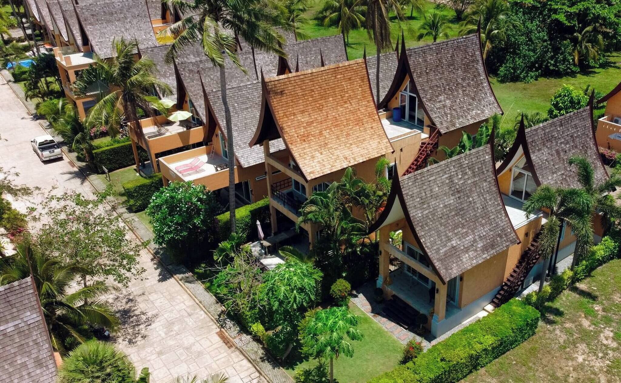 A resort with multiple bungalow-style buildings, each with a sloped roof and surrounded by lush greenery.