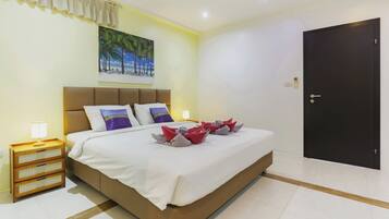 A hotel room with a bed, a painting, a door, and a nightstand.