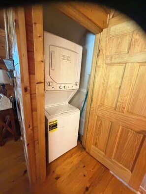 Ein kleiner Hauswirtschaftsraum mit Waschmaschine und Trockner, Holzwänden und einer Tür.
