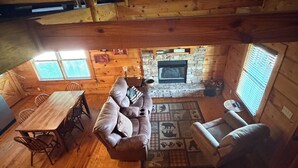 Un interior de cabaña acogedor con una mesa de comedor de madera, un sofá y una chimenea.