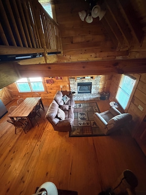 Ein gemütliches Blockhaus-Interieur mit einem Holzesstisch, einer Couch und einem Kamin.