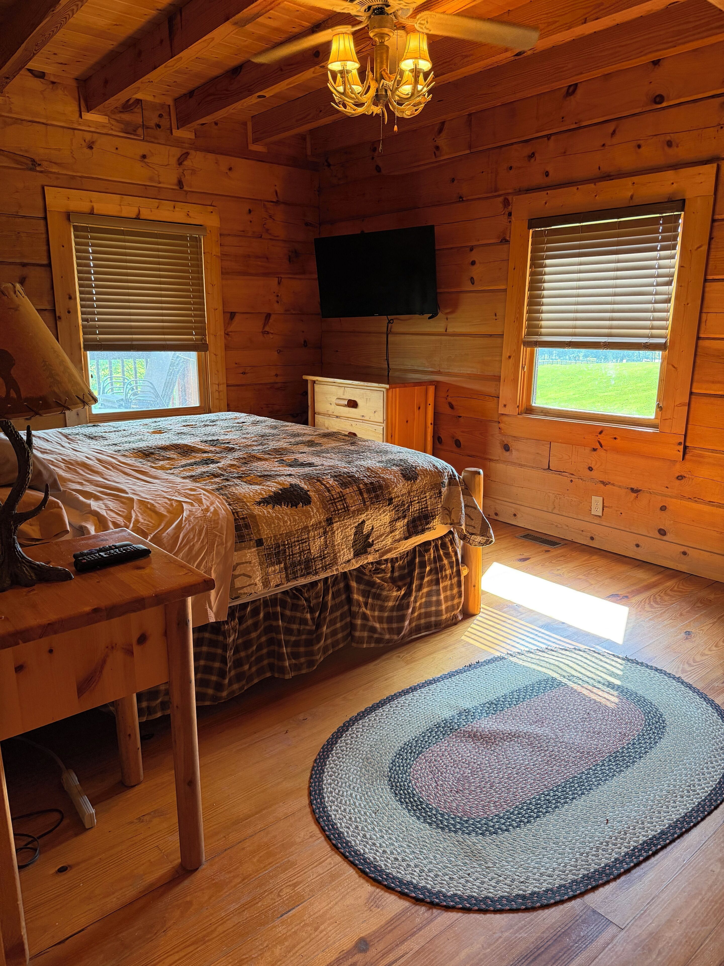 Un dormitorio de cabaña de madera con cama, cómoda y televisor en la pared.