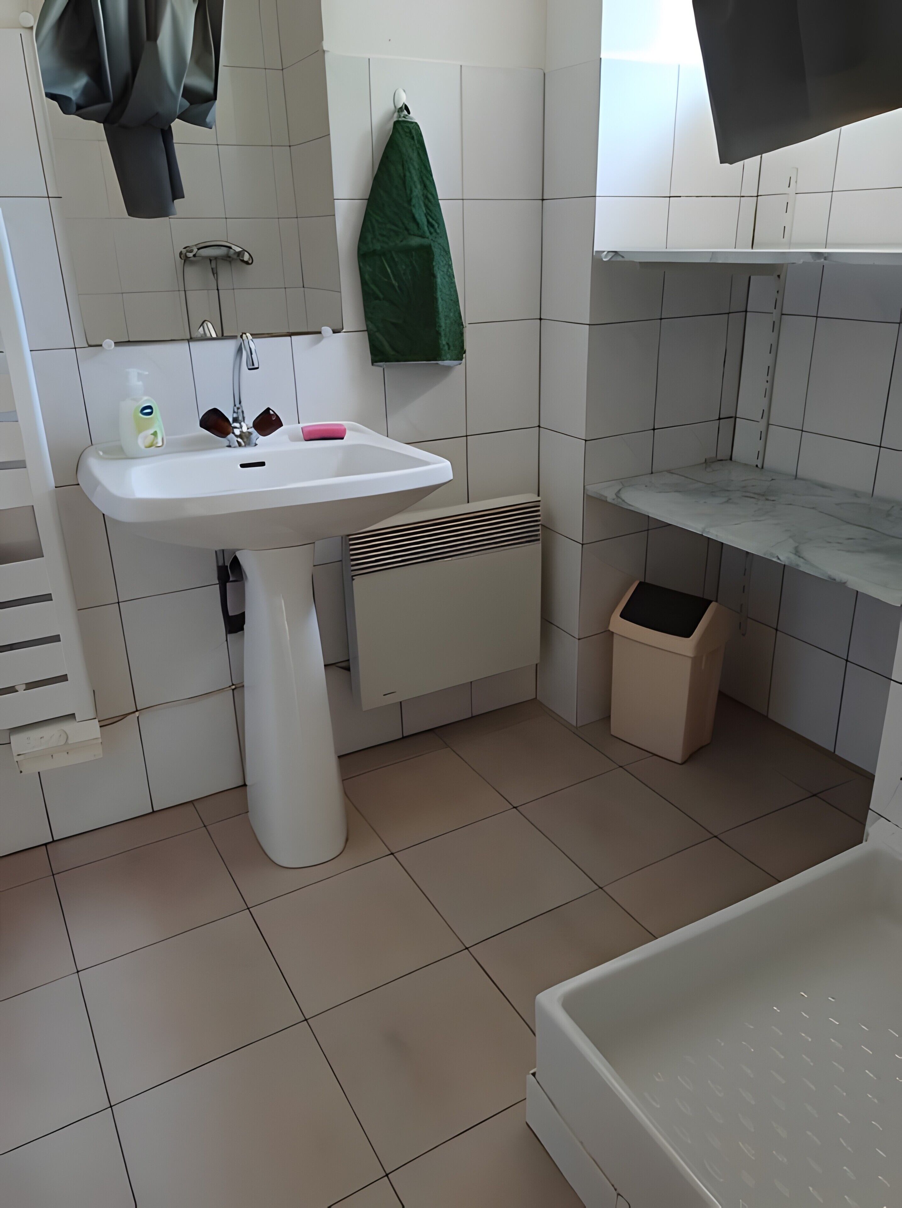A bathroom with a white sink, a green towel, a white toilet, and a white bathtub.