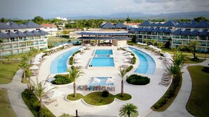 Ett semesterhotell med en central pool, flera avslappningsområden och utsikt över det omgivande landskapet.