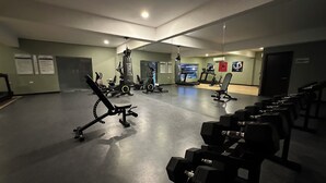Ett gym med olika typer av träningsutrustning, inklusive löpband, motionscyklar och styrketräningsmaskiner.